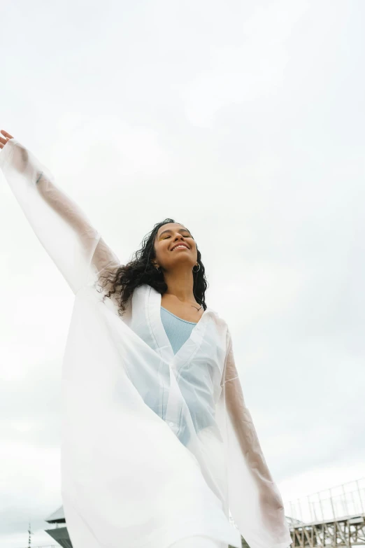 a woman in a white dress is flying a kite, an album cover, pexels contest winner, happening, pose(arms up + happy), white cloak, unsplash transparent, girl in raincoat