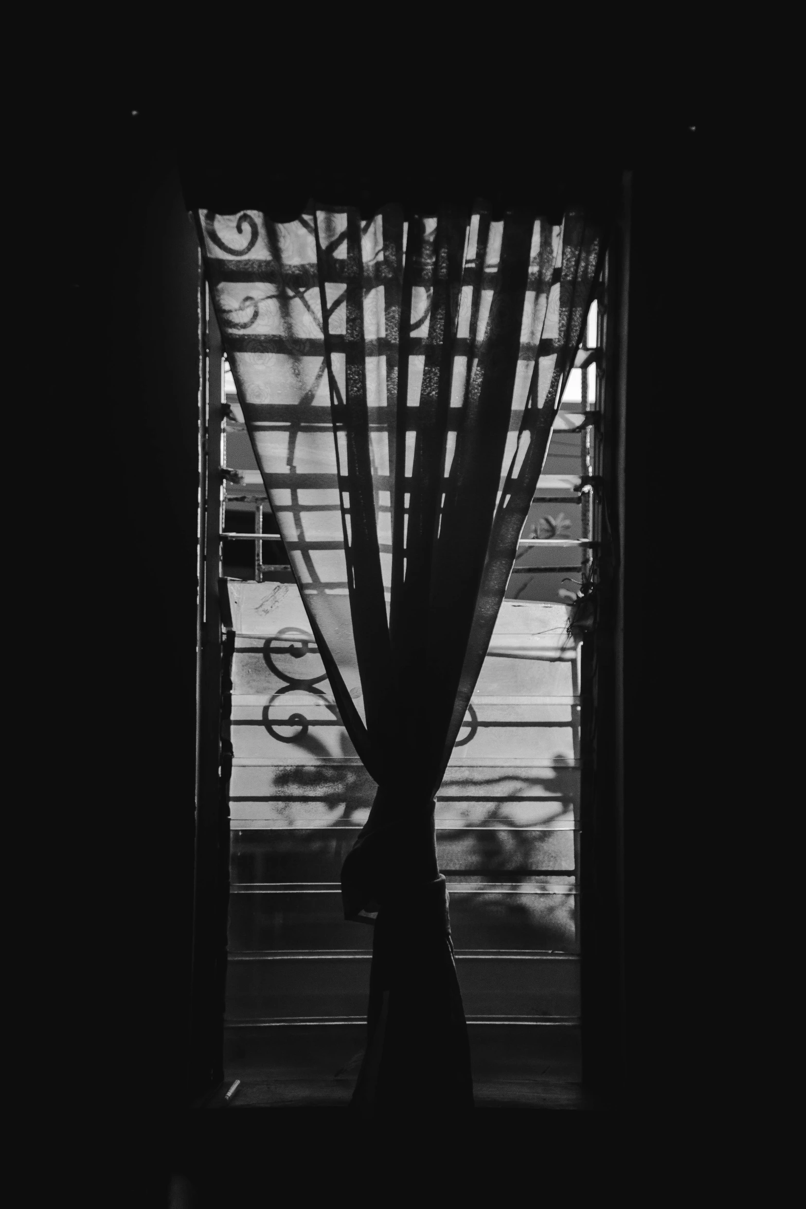 a black and white photo of a window with curtains, inspired by André Kertész, unsplash, lo-fi, silhouette, lo - fi