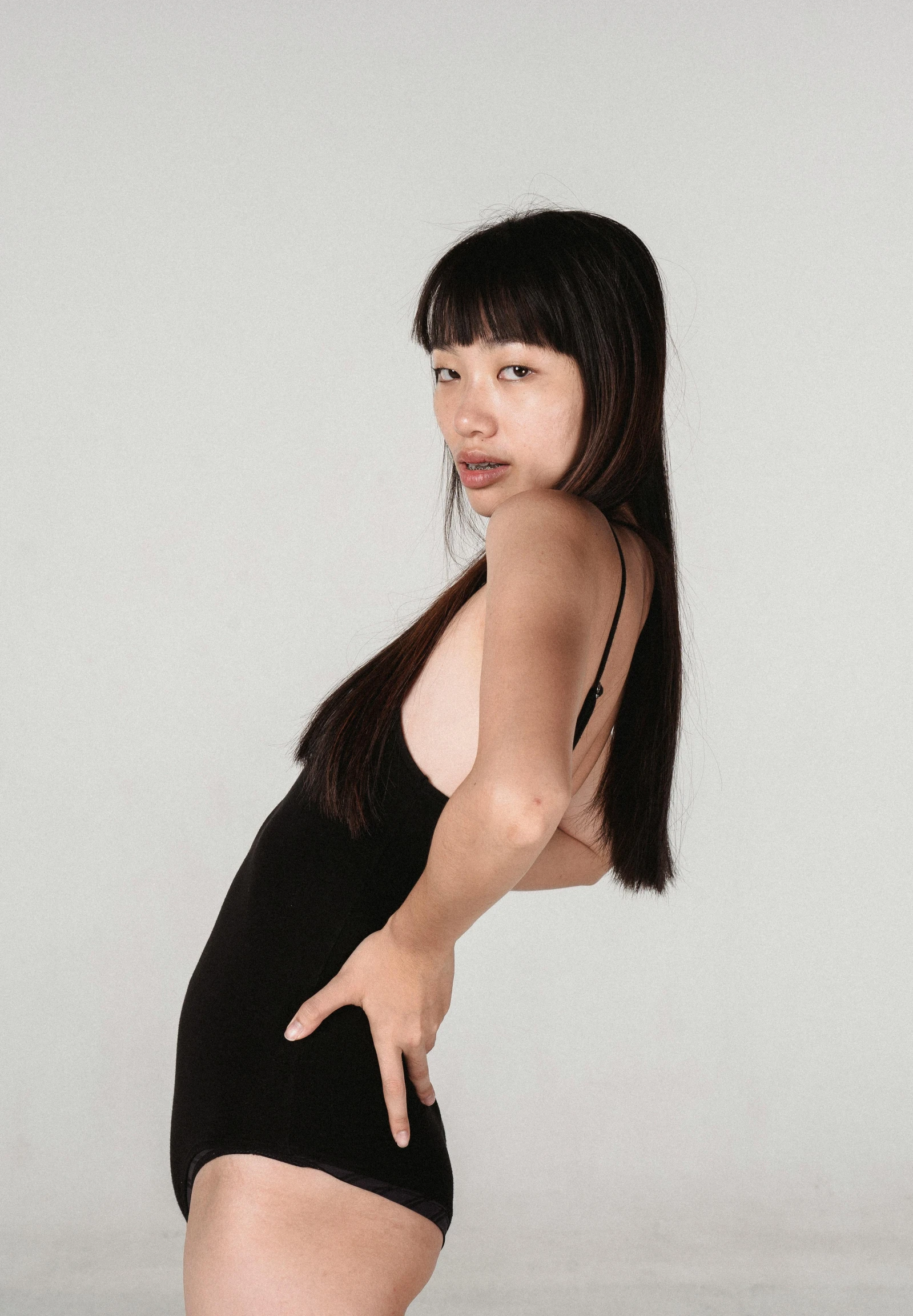 a woman in a black dress posing for a picture, an album cover, inspired by Wang E, reddit, she is wearing a black tank top, pose 4 of 1 6, half asian, basia tran