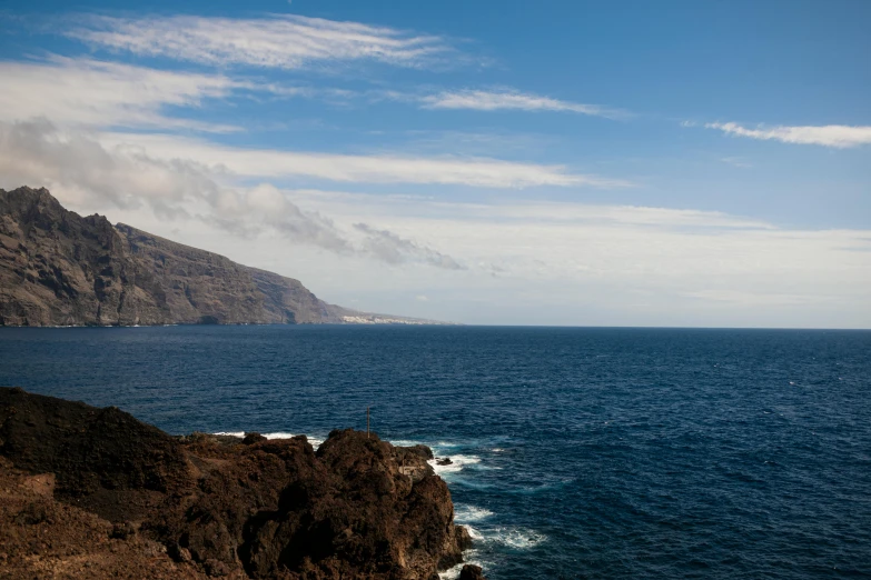 a man standing on top of a cliff next to the ocean, les nabis, volcanic, landscape photo