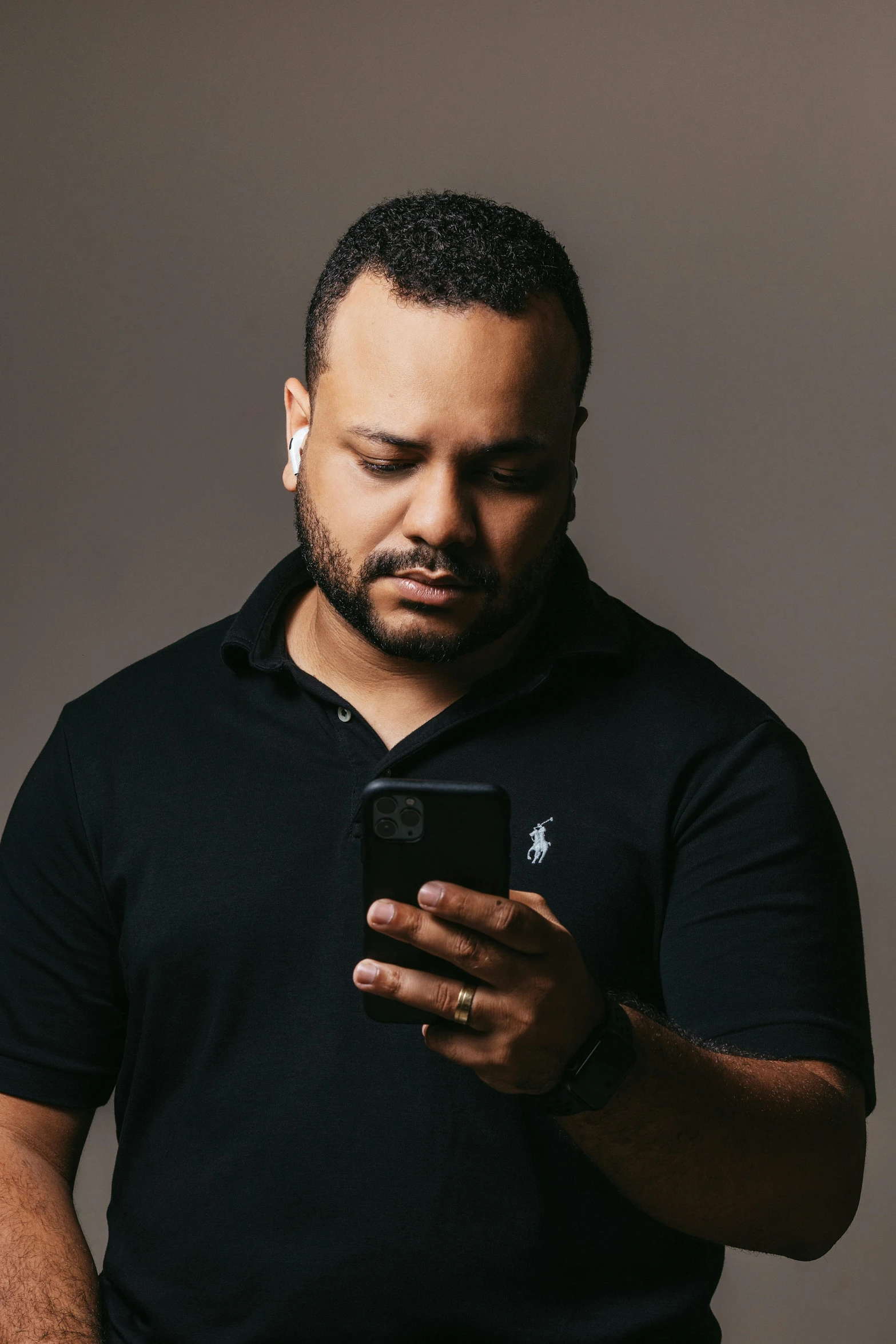 a man in a black shirt looking at his cell phone, an album cover, pexels, les nabis, riyahd cassiem, beefy, professional profile photo, looking towards camera