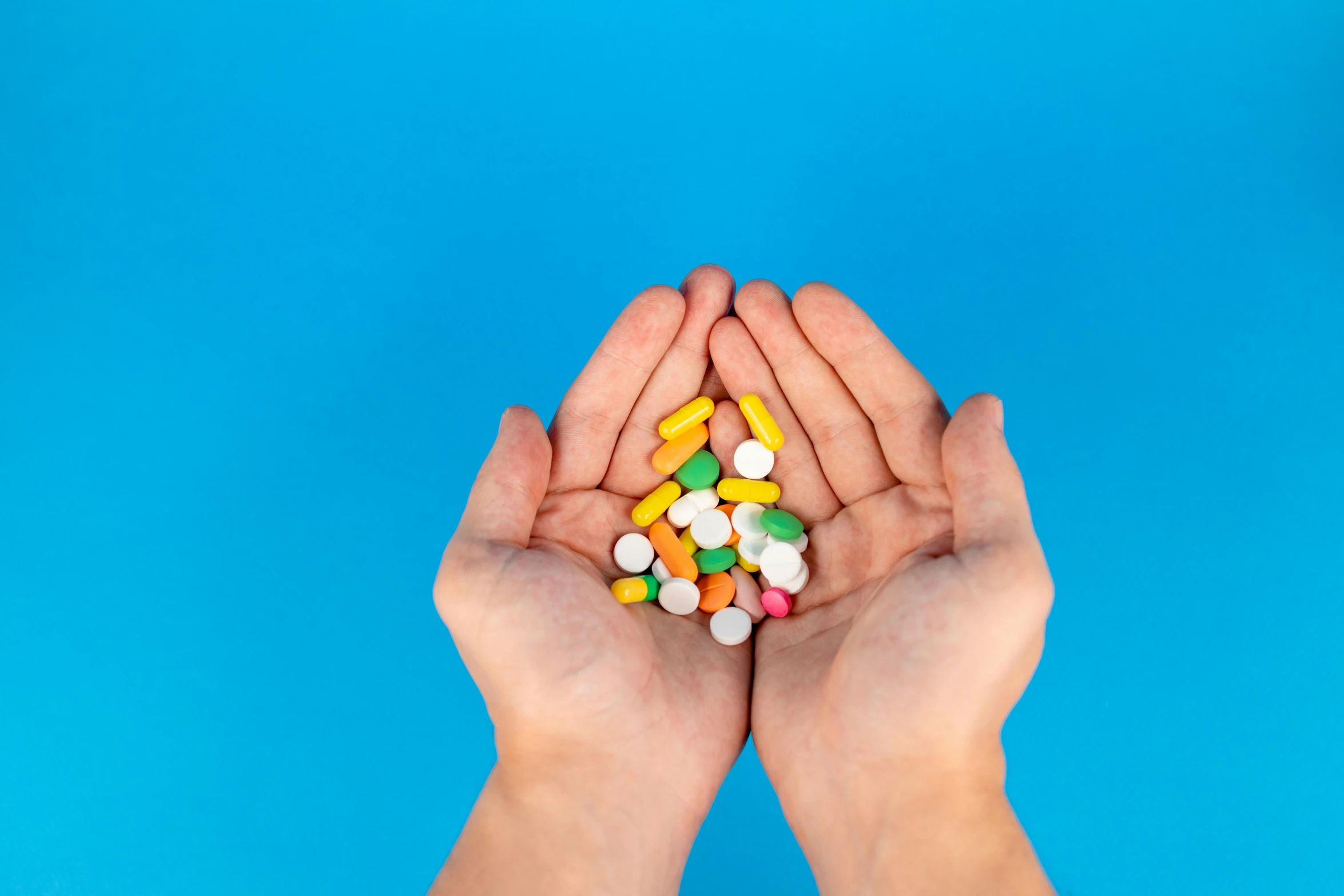 a person holding a handful of pills in their hands, inspired by Damien Hirst, pexels, antipodeans, chartreuse and orange and cyan, multi colour, small shoulders, 3 4 5 3 1