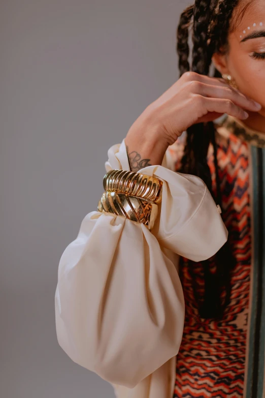 a woman taking a picture of herself in a mirror, an album cover, by Nina Hamnett, trending on pexels, baroque, gold bracelet, ball shaped accordion sleeve, white soft leather model, detailed product image