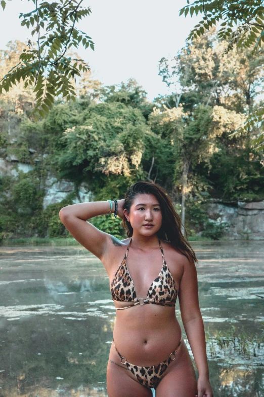 a woman in a bikini standing next to a body of water, filled with fauna, attire: bikini, a young asian woman, spotted