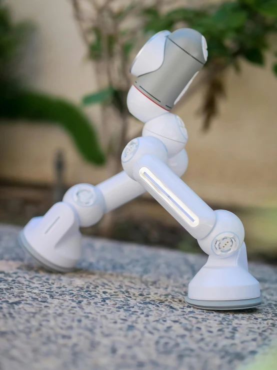 a white robot sitting on top of a sidewalk, articulated joints, product introduction photos, oscar award winning, salvia droid