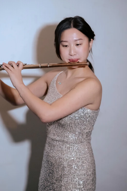 a woman in a silver dress playing a flute, inspired by Zheng Xie, unsplash, low quality photo, yanjun chengt, head and shoulder shot, <pointé pose>;open mouth