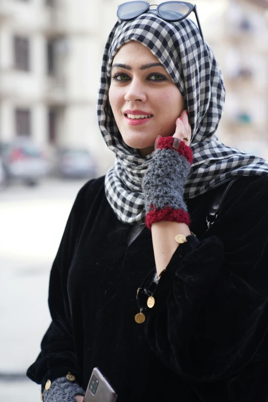 a woman in a scarf talking on a cell phone, an album cover, pexels, hurufiyya, fingerless gloves, red and white and black colors, arabic, casually dressed