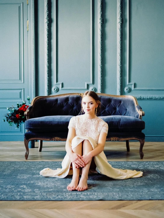 a woman sitting on a couch in a room, by Sara Saftleven, trending on unsplash, baroque, in wedding dresses, navy blue carpet, pale blue outfit, sydney sweeney