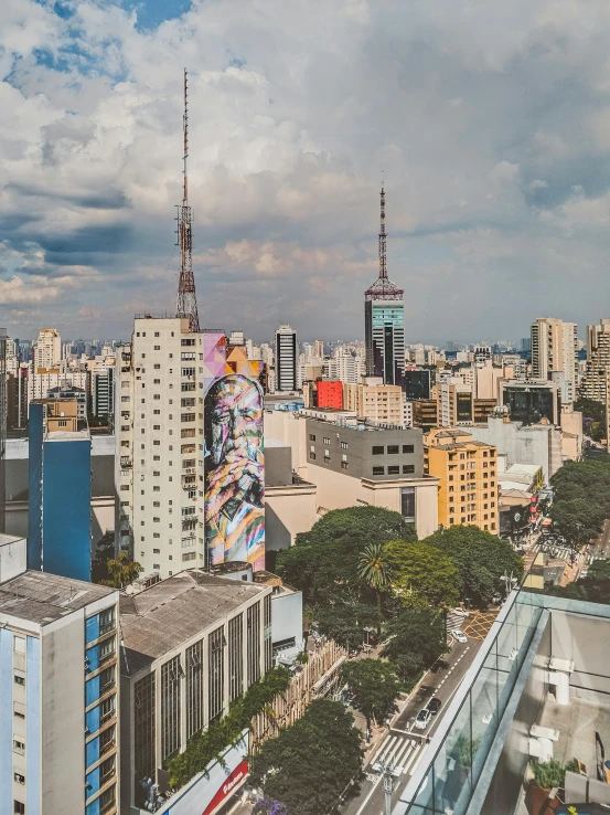 a view of a city from the top of a building, inspired by Francis Souza, graffiti, freddy mamani silvestre facade, towering above a small person, panoramic, colorful mural on walls