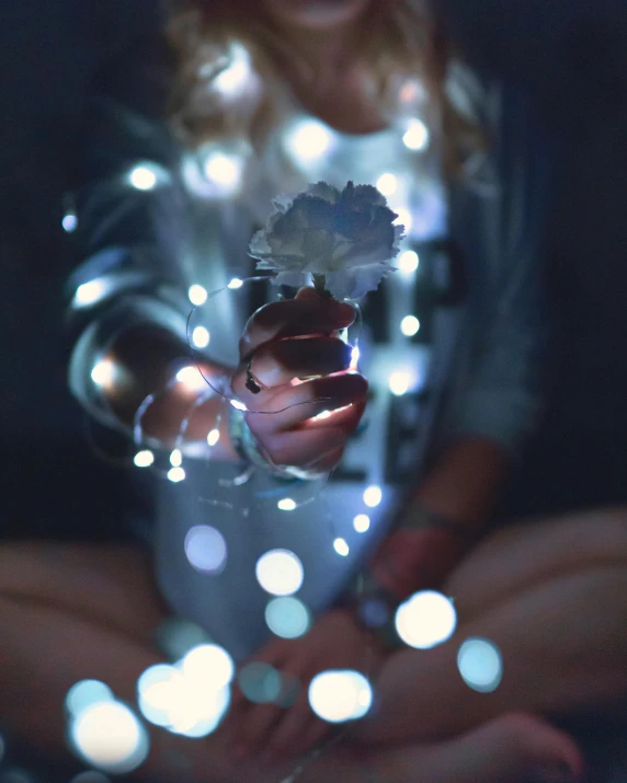 a woman holding a string of lights in her hands, inspired by Elsa Bleda, unsplash, snapchat photo, multiple stories, gypsophila, ariana grande photography