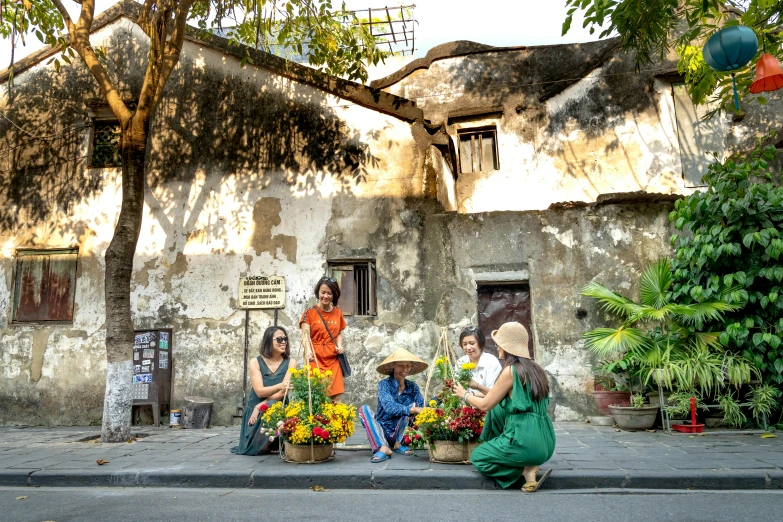 a group of women sitting on the side of a road, by Liza Donnelly, pexels contest winner, flower shop scene, vietnamese temple scene, colonial house in background, background image