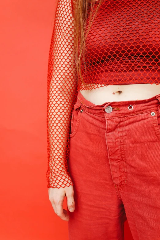a woman standing in front of a red background, an album cover, inspired by Elsa Bleda, trending on pexels, her belly button is exposed, fishnet, high angle close up shot, woman in streetwear