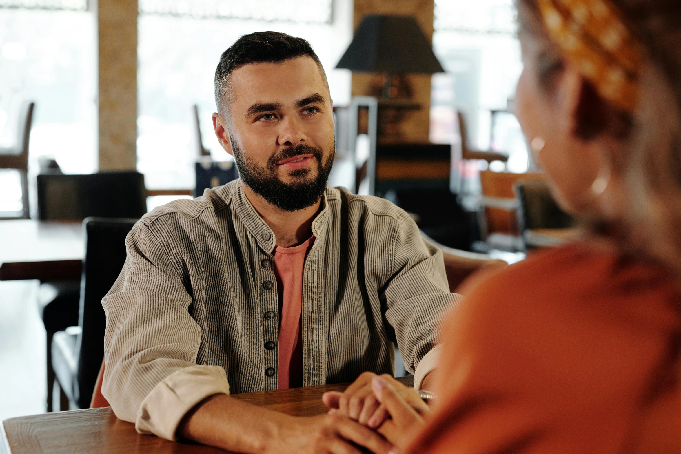 a man sitting at a table talking to a woman, trending on pexels, hurufiyya, aboriginal australian hipster, comforting and familiar, realistic professional photo, te pae