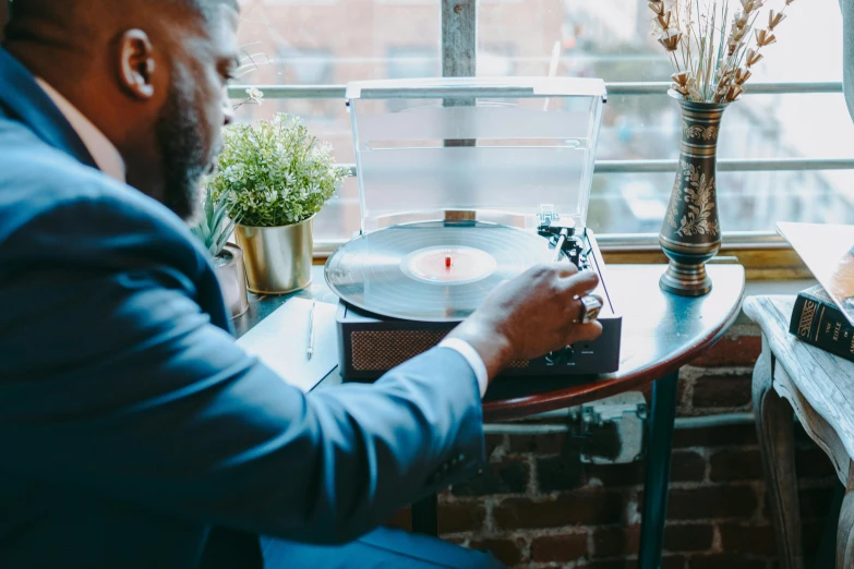 a man sitting at a table in front of a record player, stunning view, curated collections, corporate memphis, thumbnail