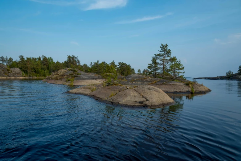 a small island in the middle of a body of water, by Jaakko Mattila, unsplash, hurufiyya, pekka halonen, rock plateau, sparse pine trees, youtube thumbnail