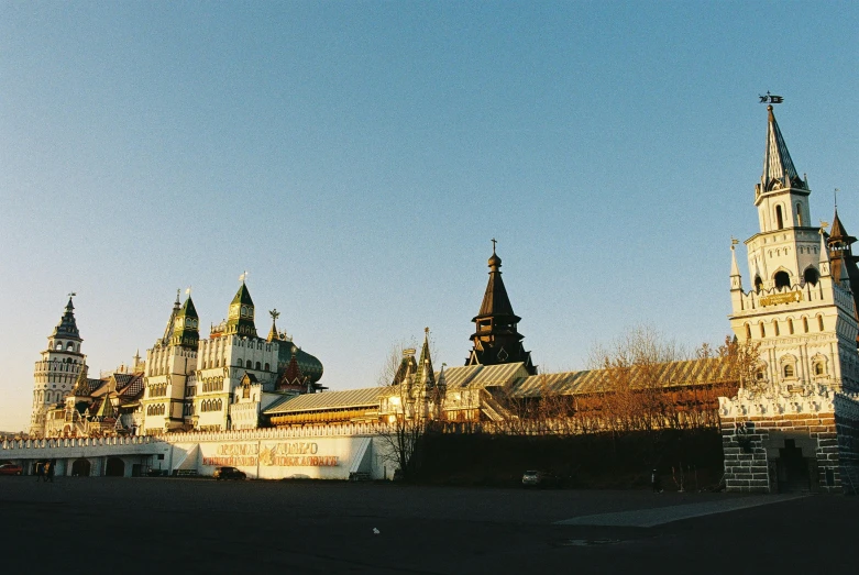 a large building with a clock tower in front of it, by Andrei Kolkoutine, unsplash, art nouveau, moscow kremlin, 1990s photograph, amusement park buildings, medium format. soft light