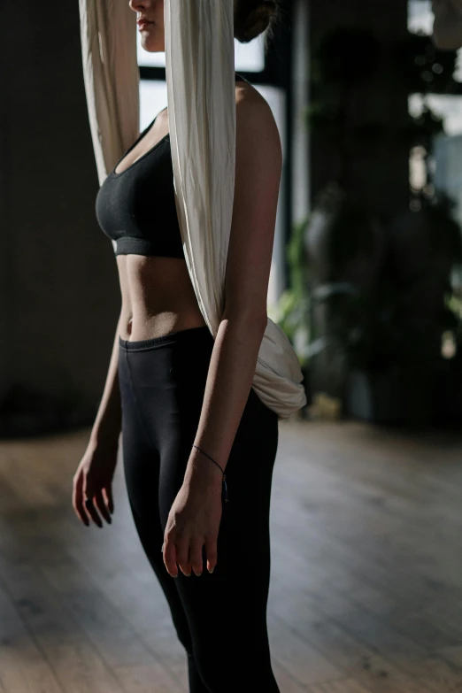 a woman standing on a skateboard in a room, detailed sports bra, large draped cloth, wearing black tight clothing, figure meditating close shot