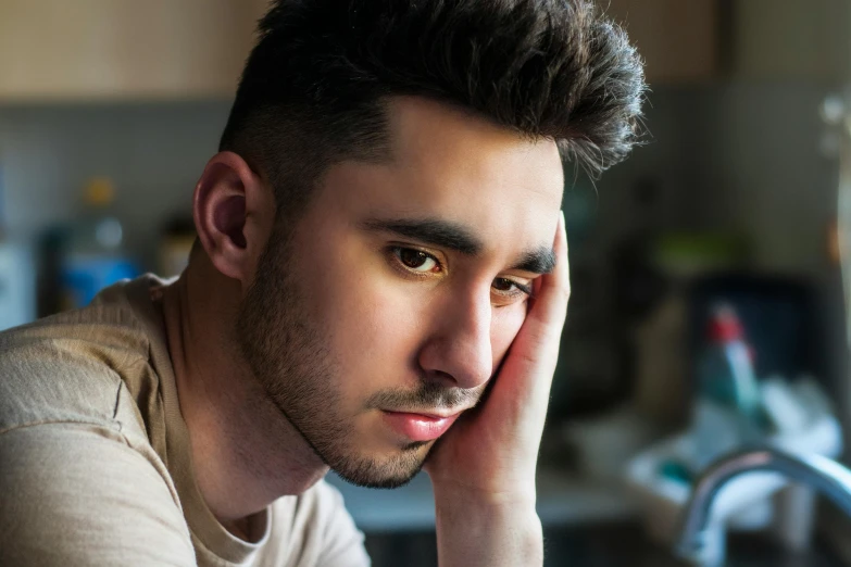 a man sitting at a table with his head in his hands, a cartoon, trending on pexels, mannerism, bisexual lighting, zayn malik, serious expressions, boy staring at the window