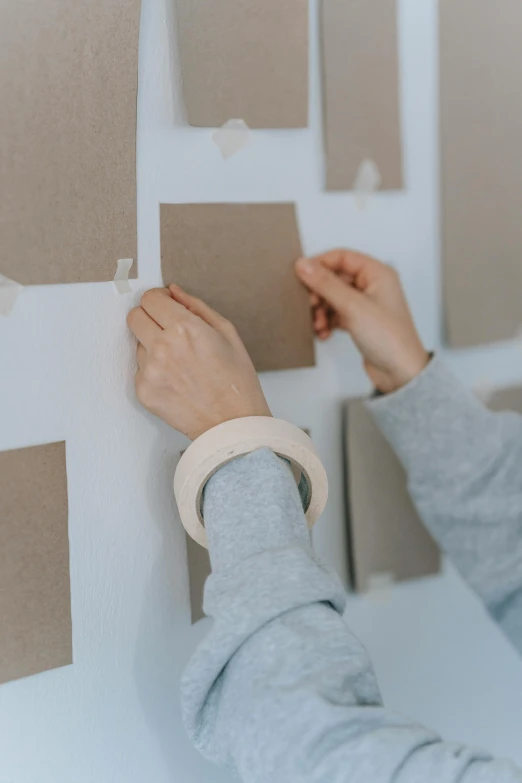 a woman placing a piece of cardboard on a wall, trending on pexels, visual art, square shapes, white sleeves, knolling, artststion
