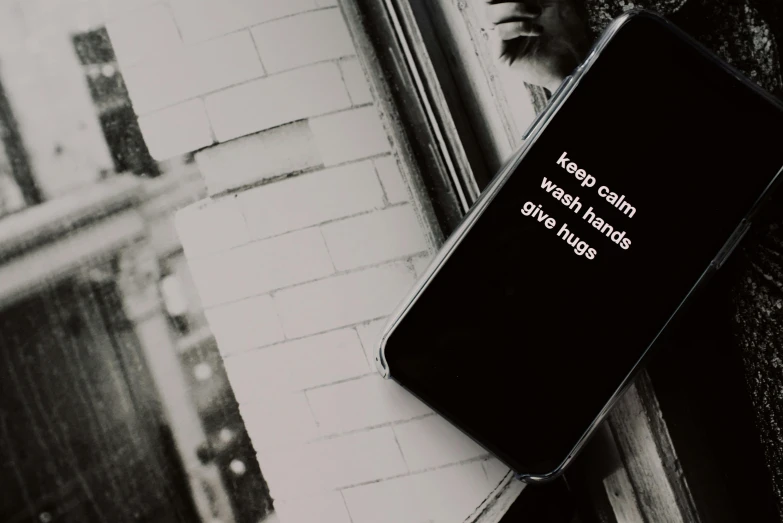 a cell phone sitting on top of a window sill, a black and white photo, unsplash, graffiti, hugs, saying, calvin klein photograph, background image