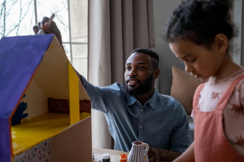 a man and a little girl playing with a doll house, pexels contest winner, arts and crafts movement, avatar image, ( ( dark skin ) ), cardboard, teaching