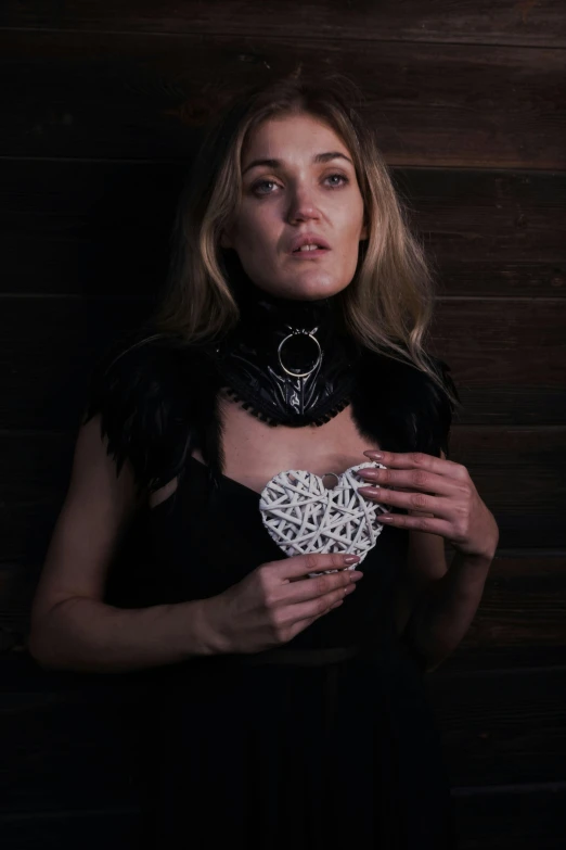 a woman in a black dress holding a white heart, an album cover, inspired by Louisa Matthíasdóttir, unsplash contest winner, renaissance, wearing detailed leather collar, made of intricate lace skeleton, sydney sweeney, 3d printed