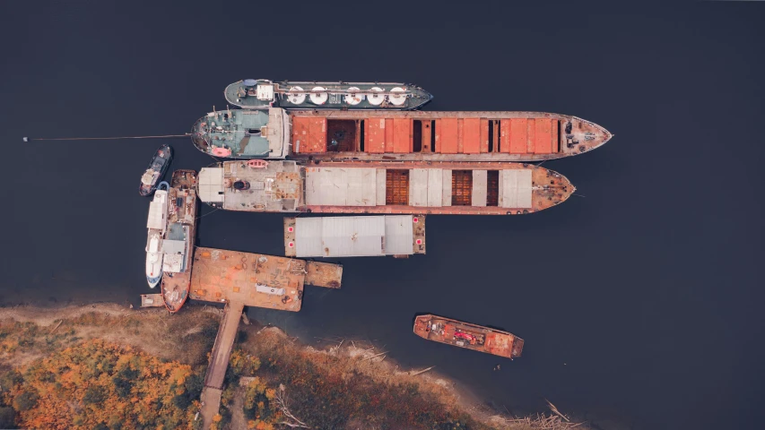 a group of boats sitting on top of a body of water, a portrait, by Adam Marczyński, pexels contest winner, utilitarian cargo ship, trading depots, drone footage, norilsk