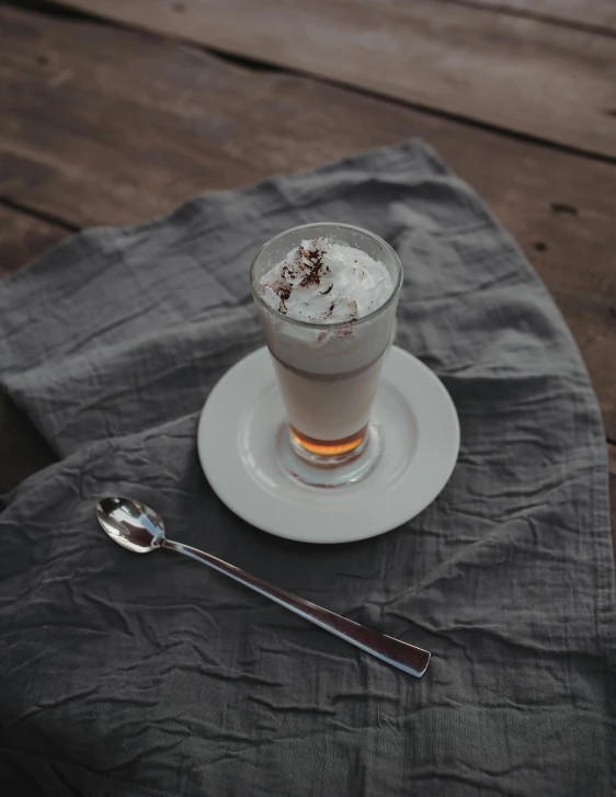 a cup of coffee sitting on top of a table, sea of parfait, spoon placed, white and pink cloth, zoomed out