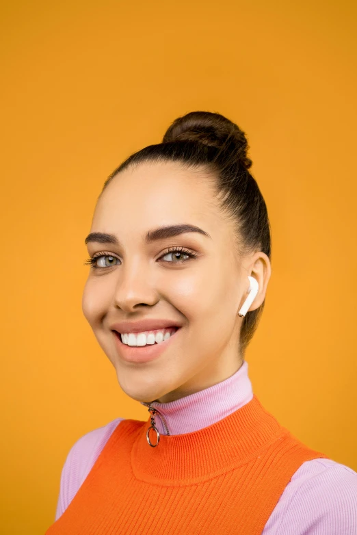 a woman in an orange top smiling at the camera, by Gavin Hamilton, trending on pexels, airpods, tight bun, avatar image, pokimane