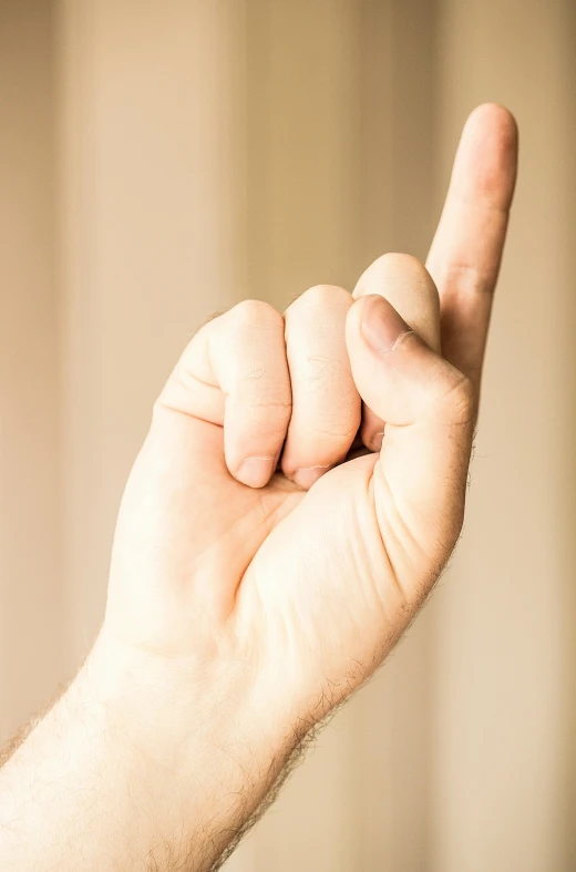 a close up of a person's hand holding a toothbrush, giving the middle finger, r-number, stick poke, expressive pose