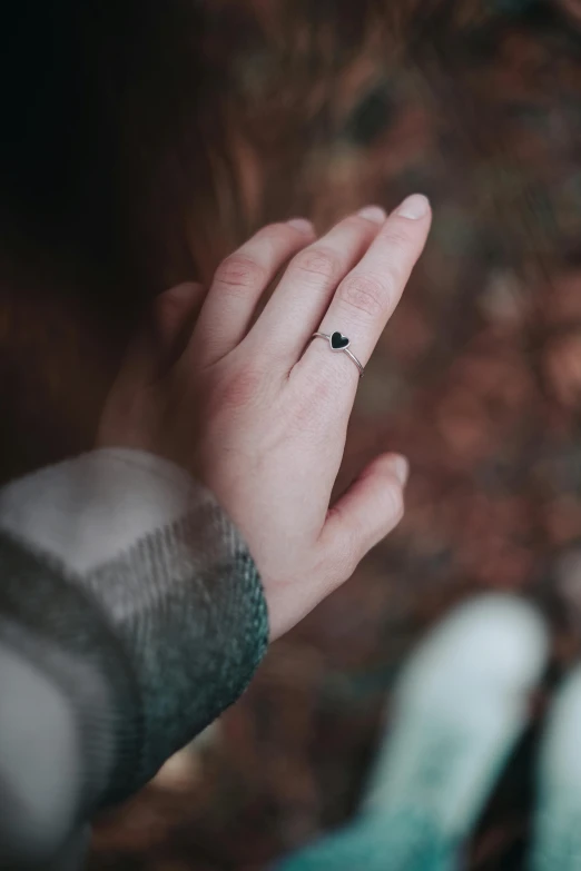 a person holding a tiny heart on their finger, a tattoo, by Julia Pishtar, trending on pexels, black jewellery, outdoors, tall, all around