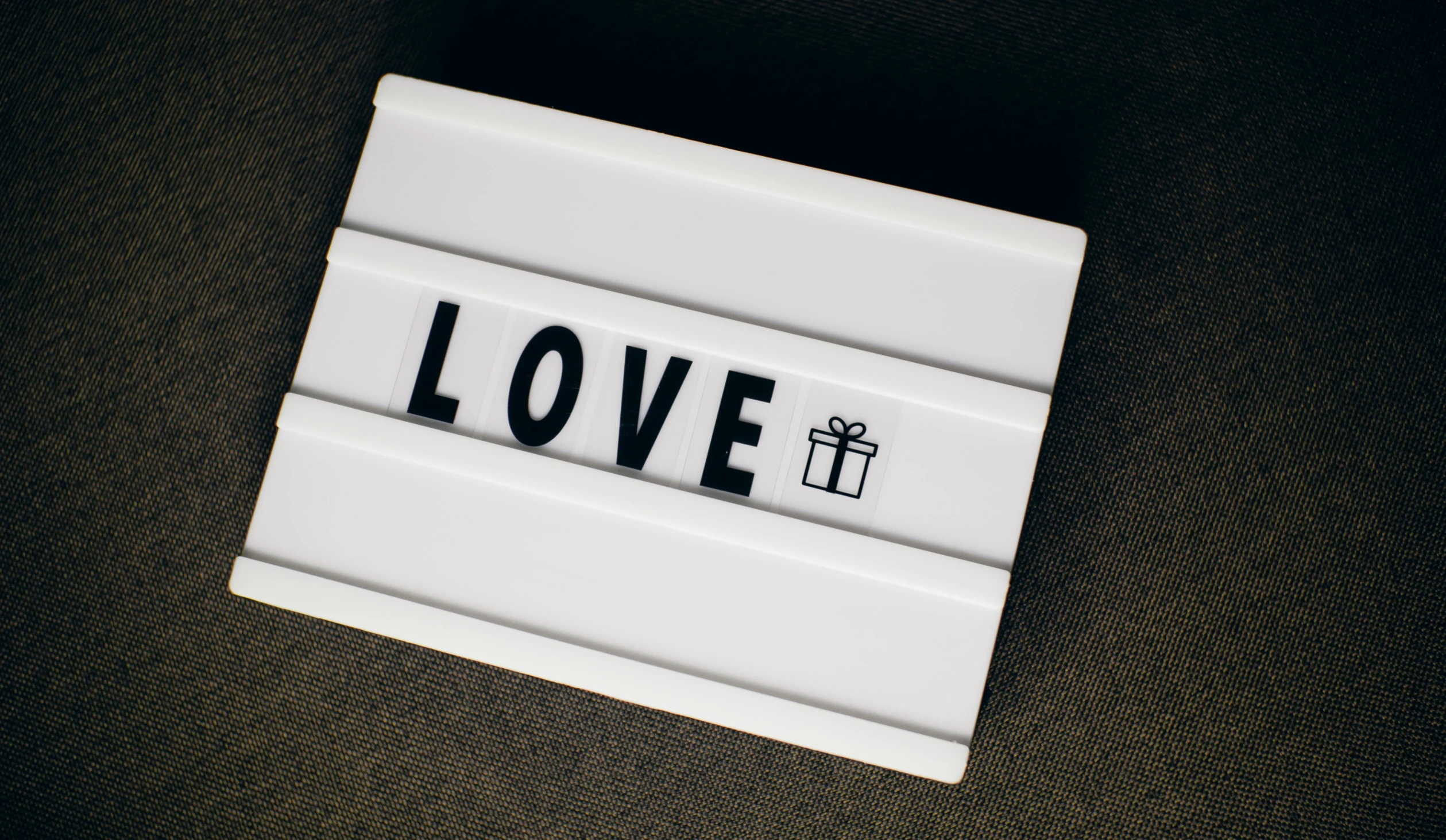 a close up of a sign with the word love written on it, a picture, by Emma Andijewska, pexels contest winner, white box, gifts, lit from the side, gif