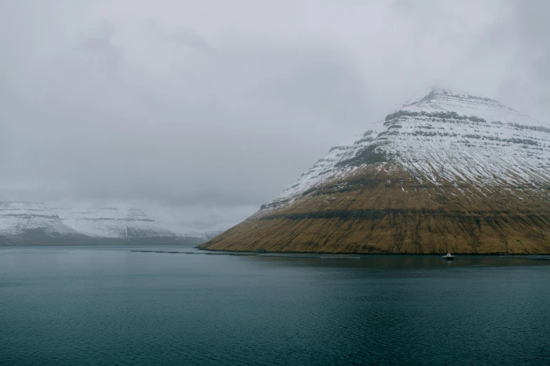 a large body of water with a mountain in the background, by Þórarinn B. Þorláksson, pexels contest winner, hurufiyya, grey, nadav kander, panorama, conde nast traveler photo