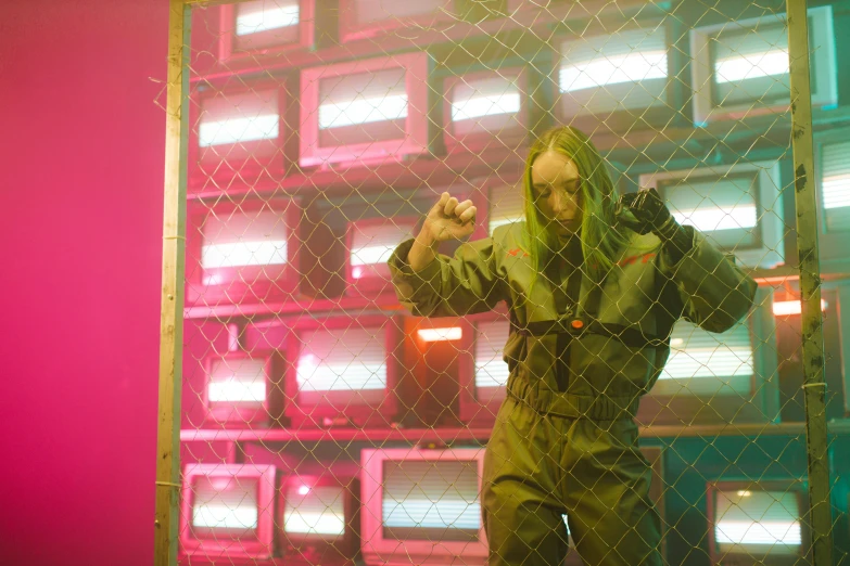 a man standing in front of a wall of televisions, cyberpunk art, inspired by David LaChapelle, billie eilish as female loki, stood in a cell, performing a music video, militaristic