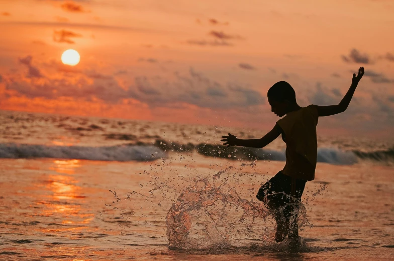 a young boy playing in the ocean at sunset, pexels contest winner, fan favorite, sri lanka, thumbnail, 8 k 4 k