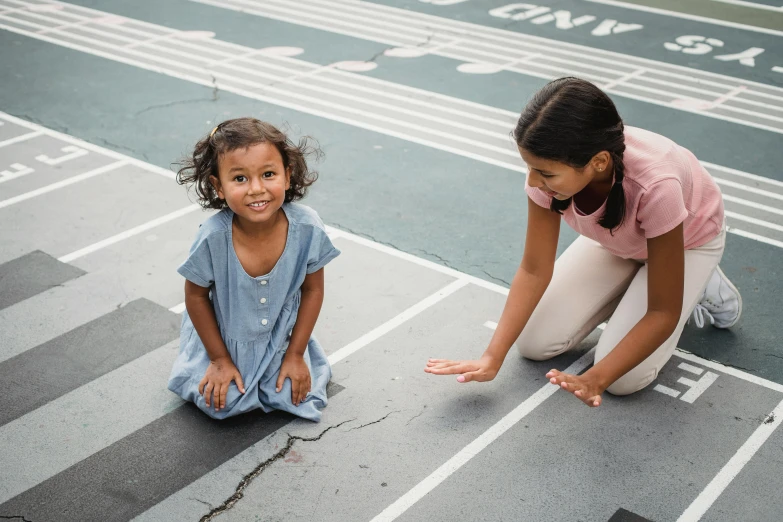 a woman kneeling on the ground next to a little girl, pexels contest winner, vancouver school, victory lap, mixed race, leading lines, in the center midground