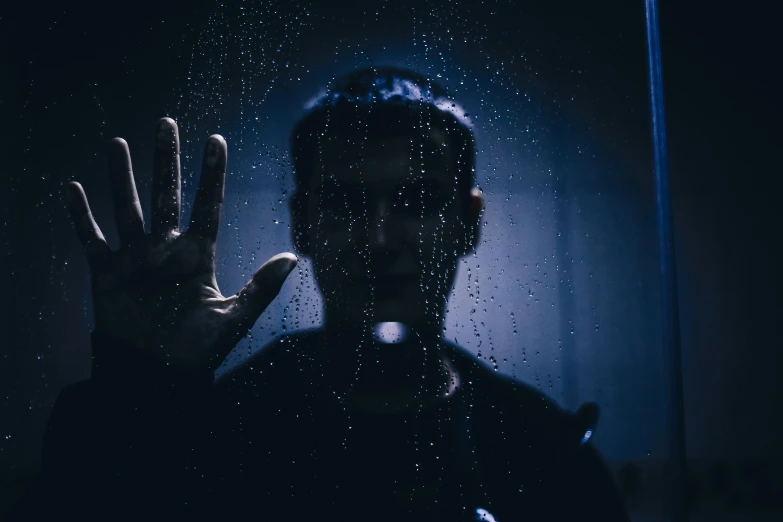 a man standing in front of a window covered in rain, pexels contest winner, conceptual art, holding up a night lamp, hand gesture, from horror movies, trapped ego