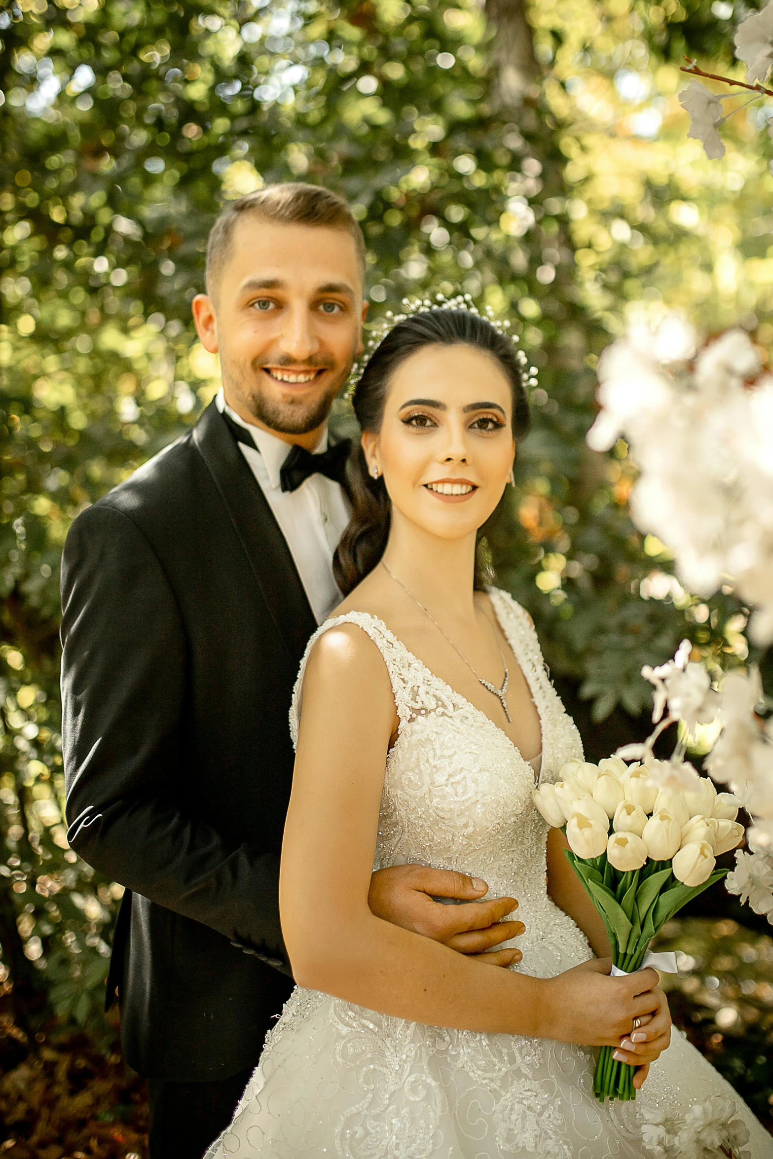 a man in a tuxedo standing next to a woman in a wedding dress, a picture, by Arthur Sarkissian, pexels contest winner, flowers in background, ayanamikodon and irakli nadar, all looking at camera, on a tree