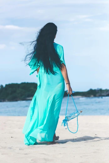 a woman standing on a beach holding a purse, inspired by Gina Pellón, happening, flowing aqua silk, long flat hair, back - shot, asian woman