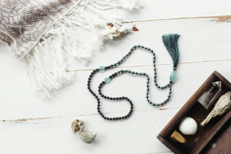 a wooden box filled with beads and a tassel, by Emma Andijewska, unsplash, hurufiyya, black and green scheme, yoga, necklace, full - length photo