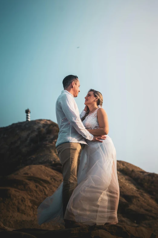 a man and a woman standing on top of a mountain, by Lee Loughridge, pexels contest winner, wedding, beach, natural soft light, looking left