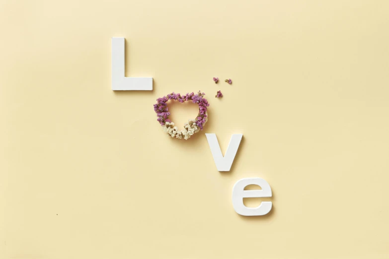 a heart made out of flowers next to the word love, an album cover, inspired by Cerith Wyn Evans, trending on pexels, lavander and yellow color scheme, detail shot, glossy white metal, miniature product photo
