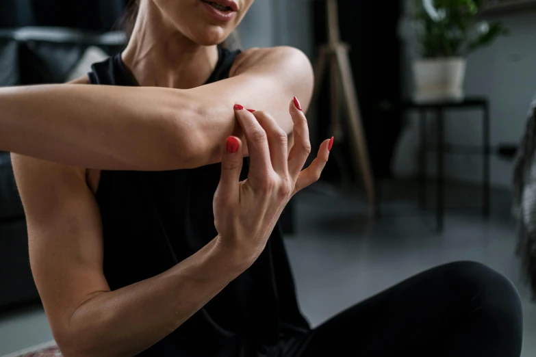 a woman sitting on the floor stretching her arms, trending on pexels, skin wounds, close up to a skinny, sitting in a lounge, manuka