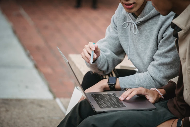 two people sitting on a bench looking at a laptop, by Carey Morris, trending on pexels, holding pencil, wearing a grey hooded sweatshirt, university, thumbnail