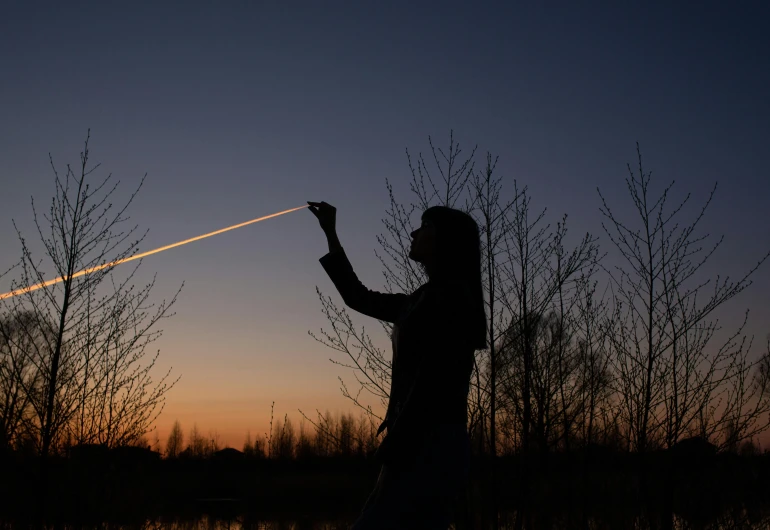 a person that is flying a kite in the sky, pexels contest winner, land art, fireball lighting her face, holding a light saber, plane light, at dusk!