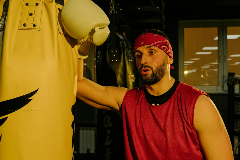 a man standing next to a punching bag, a portrait, inspired by Volkan Baga, pexels contest winner, hurufiyya, sam hyde in gold suit, thumbnail, wearing fitness gear, h3h3