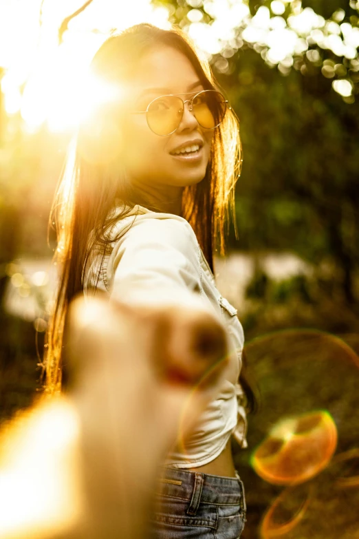 a woman pointing her finger at the camera, by Niko Henrichon, trending on pexels, sun flairs, 5 0 0 px models, hippie, asian sun