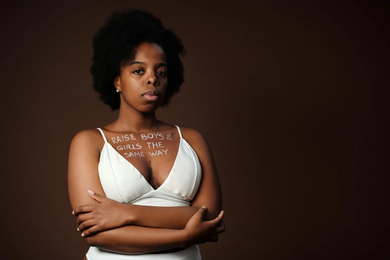 a woman with a message on her chest, by Lily Delissa Joseph, pexels contest winner, ( ( brown skin ) ), white ribbon, various posed, afro