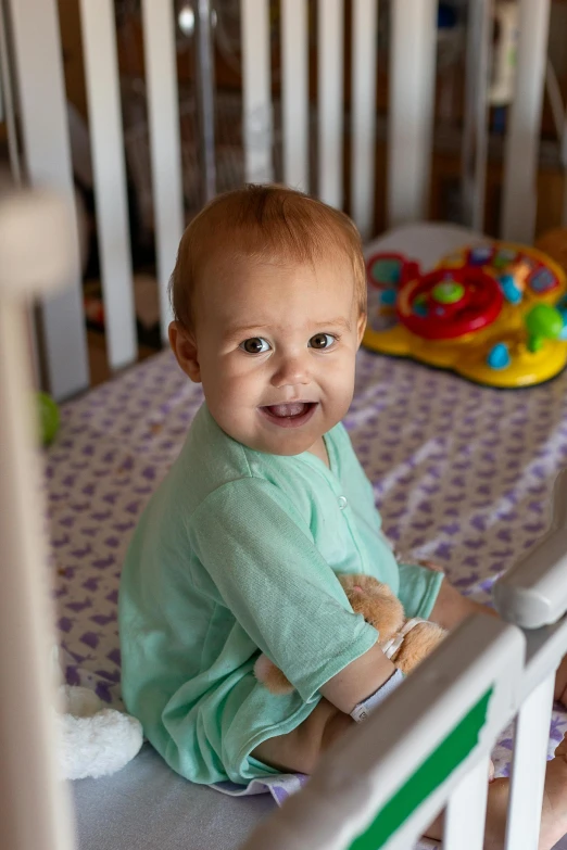 a baby sitting in a crib smiling at the camera, medical, profile image, conor walton, children's