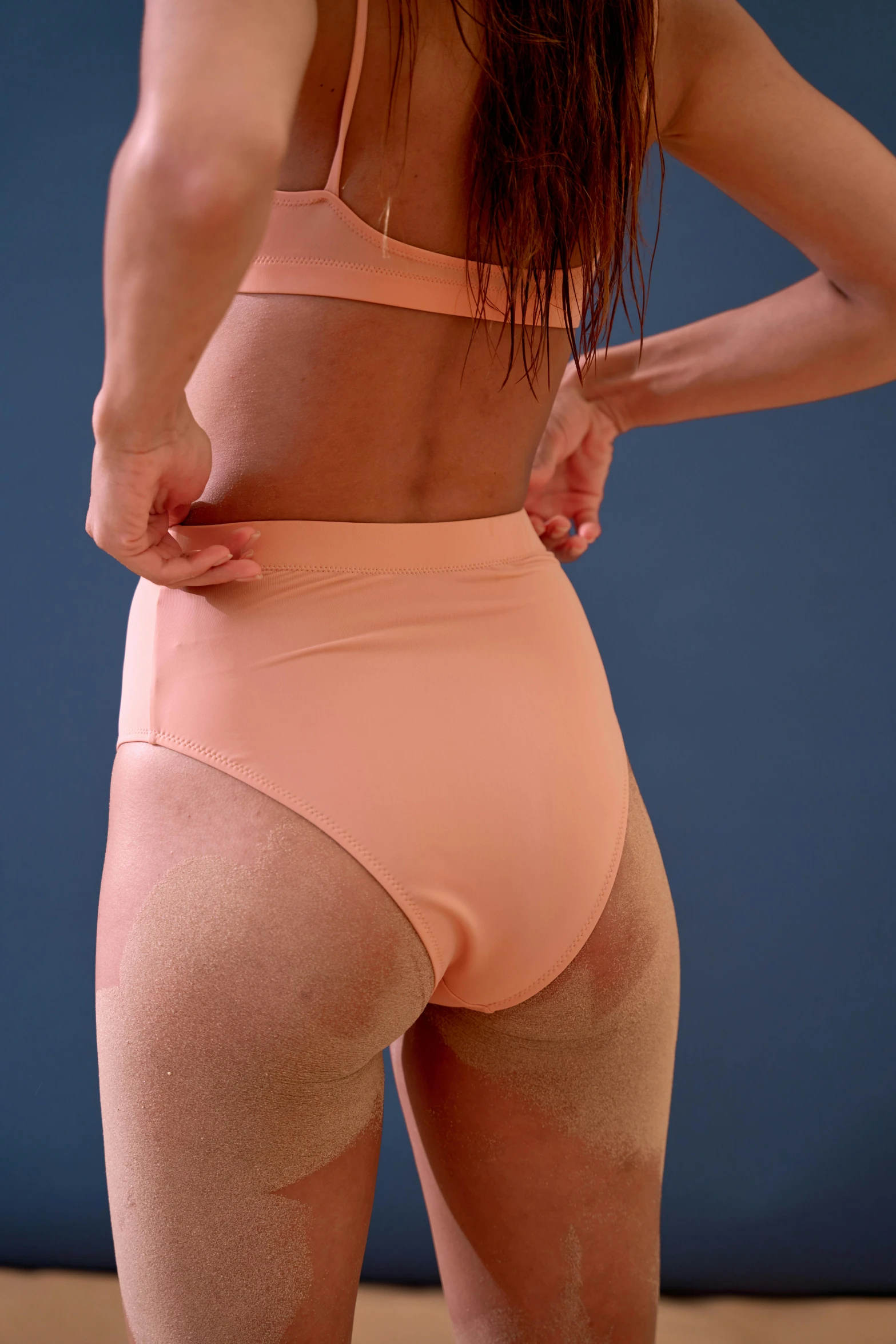 a woman in a pink underwear standing in front of a blue wall, inspired by Vanessa Beecroft, unsplash, toned orange and pastel pink, bend over posture, zoomed out view, performance